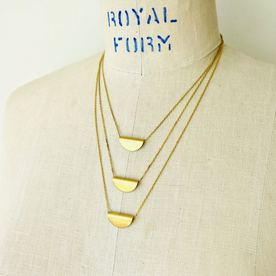 Tiered Amplify Necklace is a layered necklace with three tiers of fine chain each with a folded brass pendant that floats freely on chain.