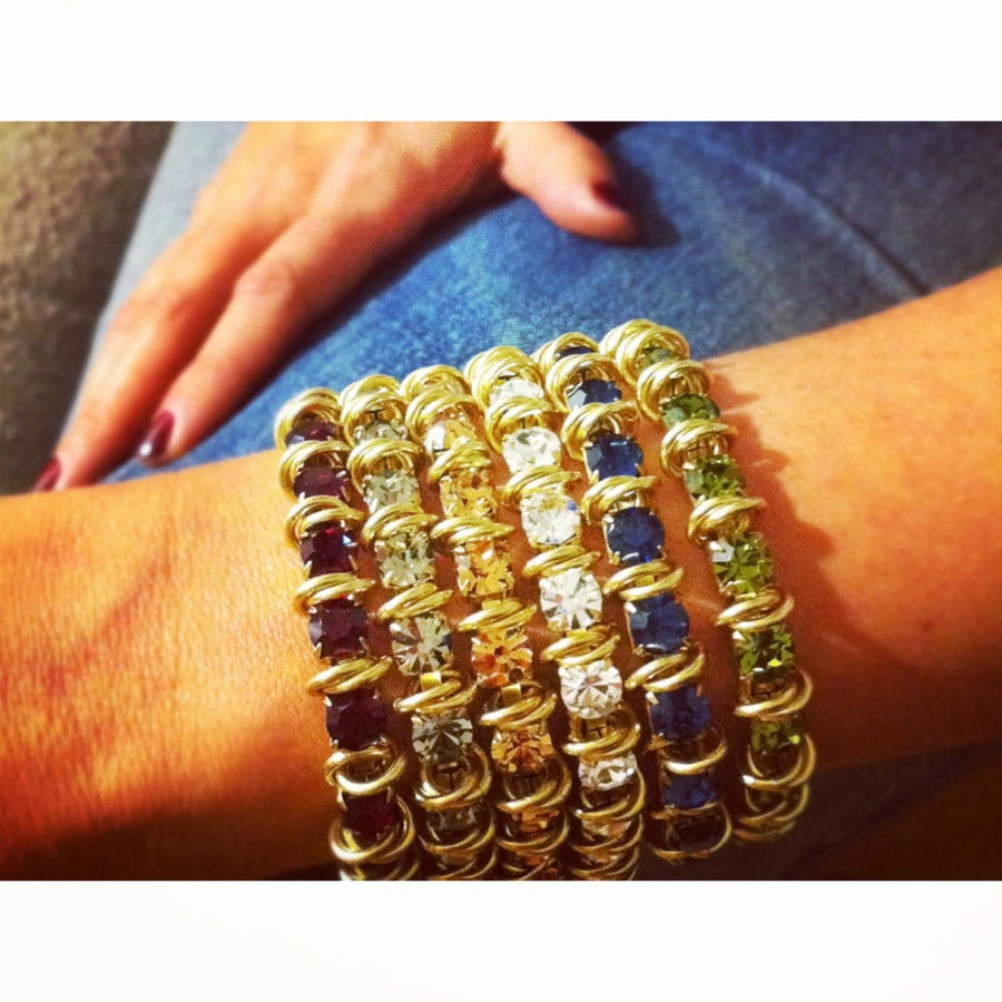 A stack of colourful MoonRox Jewelled Bracelets on wrist. Modern tennis bracelet made with rhinestone chain and brass accents.
