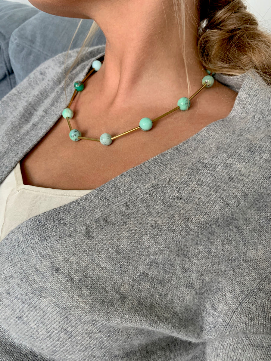 Resilience Necklace by MoonRox can be worn as a lariat or a necklace. Semi-precious stones are spaced along brass components. This photo shows the necklace in 