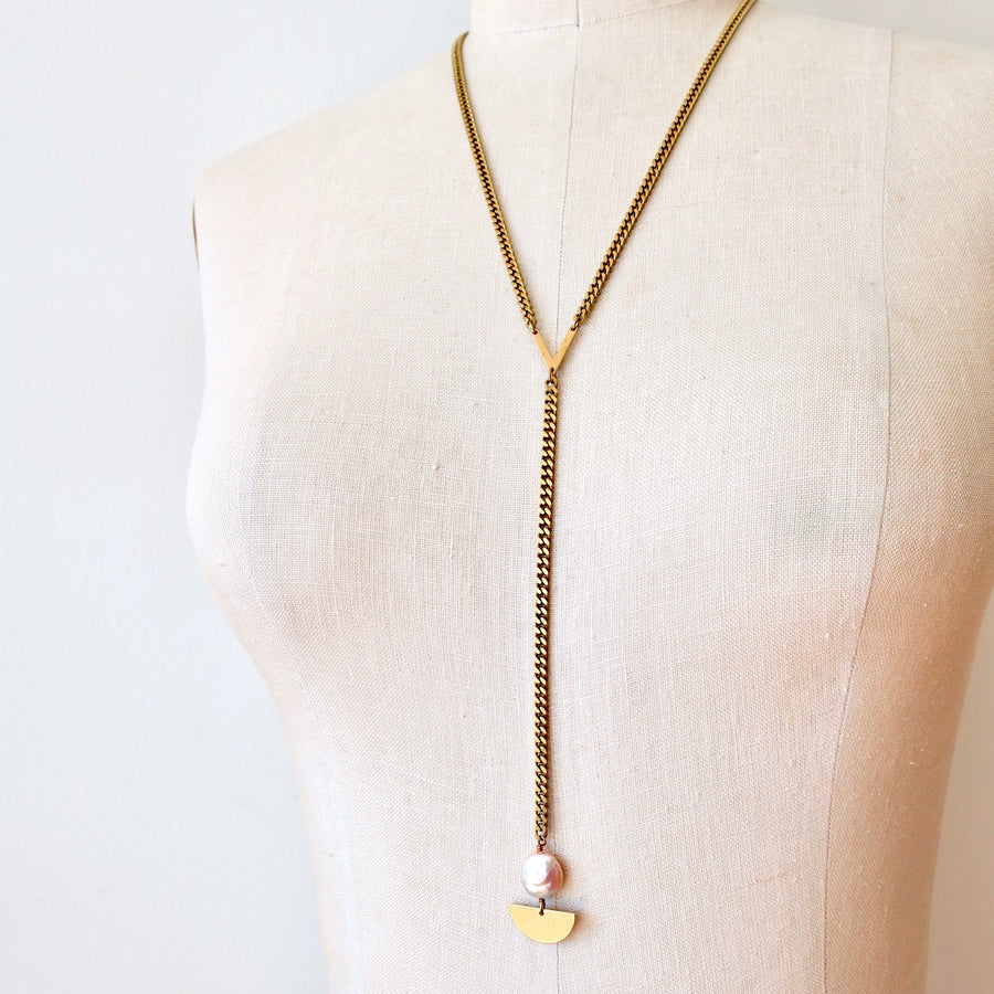 Sail Away With Me Lariat is a Y-style chain necklace with lustrous coin-shaped freshwater pearl and brass semi-circle detail