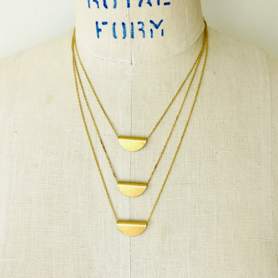 Tiered Amplify Necklace is a layered necklace with three tiers of fine chain each with a folded brass pendant that floats freely on chain.