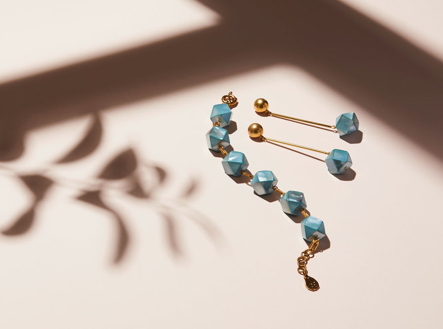 Azzurra Earrings are stud earrings with cool blue mother of pearl beads that hang below elongated rods. Shown with matching bracelet.