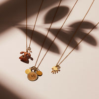 Share a greeting with the Hello, Token or Hi Five Necklaces made with brass charms and freshwater pearl. 