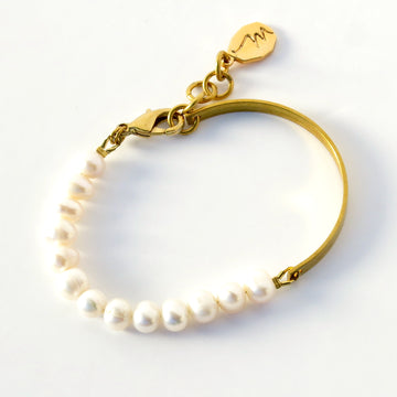 Illuminated Bracelet with one half consisting of a string of pearls and the other half a solid brass band.
