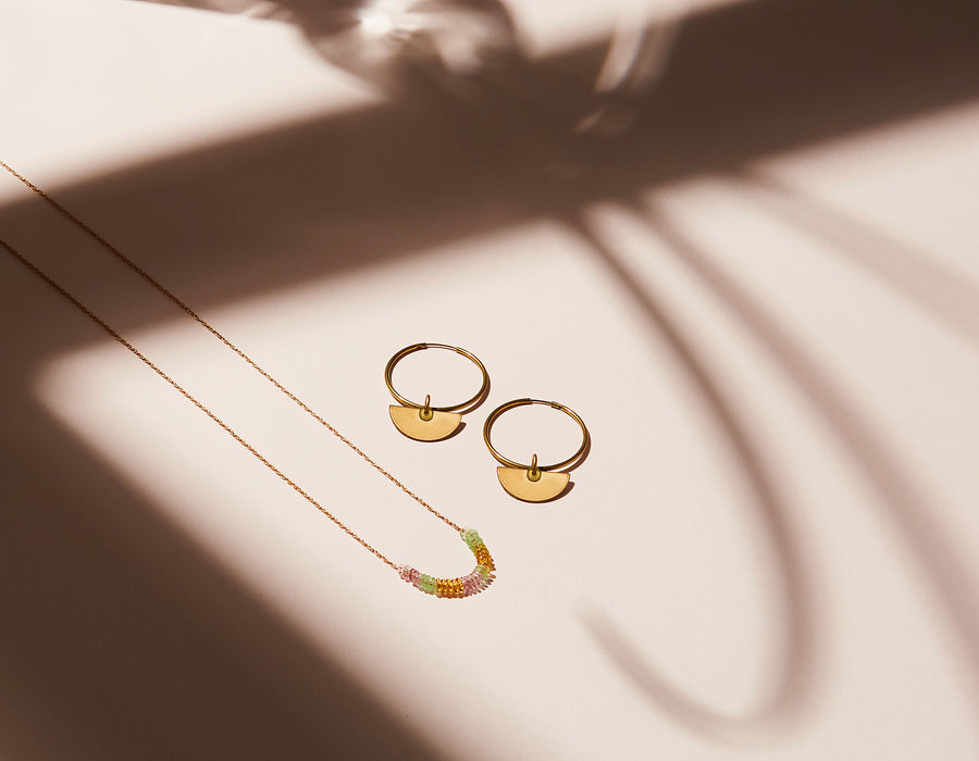 Inner Circle Necklace features a fine brass chain with a carefully arranged series of little colourful glass loops that float along the chain. Shown with matching Hoop Earrings. Made in Toronto, Canada by MoonRox Jewellery & Accessories.