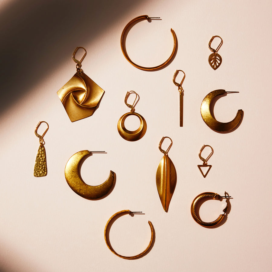 The Sleek Hoops are made of brass with a smooth rounded finish. They measure 45mm in diameter. Shown with a selection of other brass charm and hoop earrings.