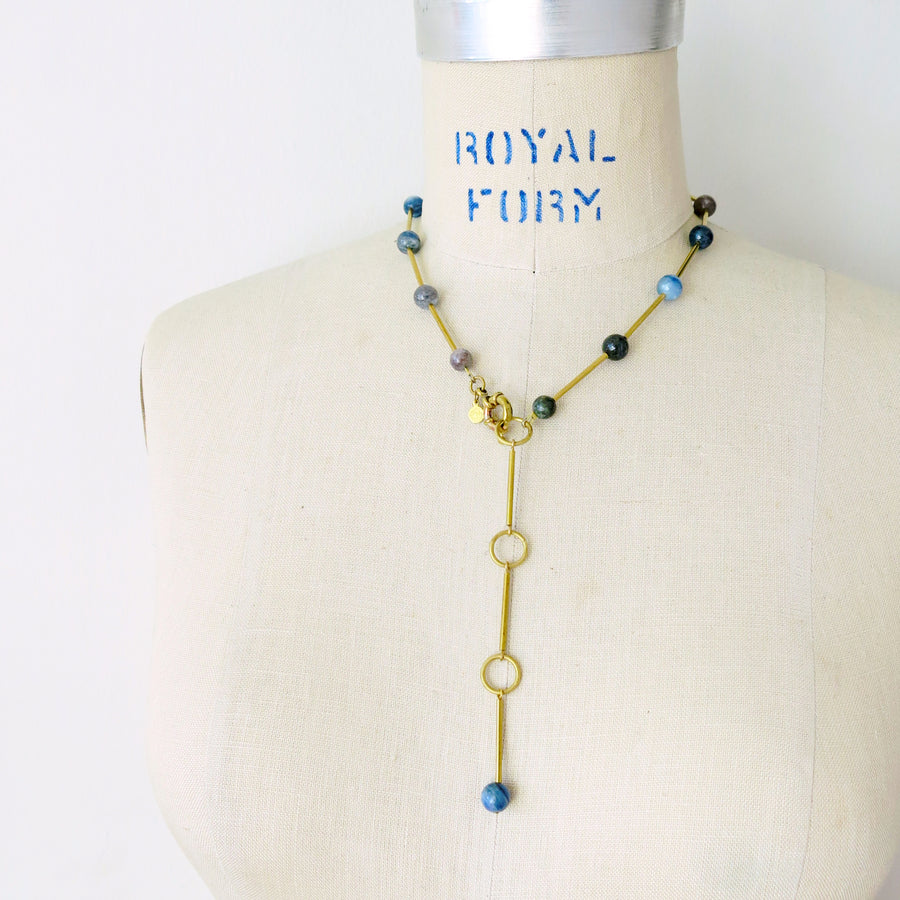 Resilience Necklace by MoonRox can be worn as a lariat or a necklace. Semi-precious stones are spaced along brass components. This photo shows the necklace as a lariat in kyanite.