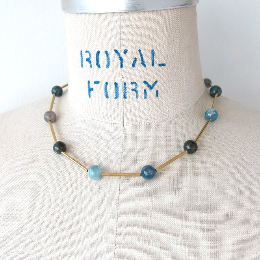 Resilience Necklace by MoonRox can be worn as a lariat or a necklace. Semi-precious stones are spaced along brass components. This photo shows the necklace in kyanite